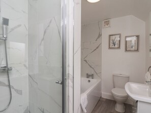 A bathroom with a glass shower enclosure, a bathtub, a toilet, and a sink. - Helmsley Cottage (York)