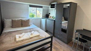 Una camera da letto con un letto, un angolo cottura e una zona pranzo separata.