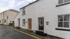 Un edificio blanco con un cartel de cine, una puerta que dice 'Little Aam' y un cartel que anuncia 'Darwin Cottage'.