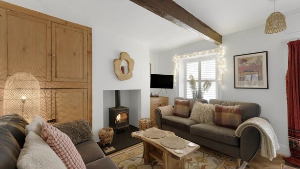 Una sala de estar acogedora con chimenea, un sofá, un televisor y una viga de madera en el techo.