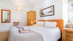 Ein Schlafzimmer mit einem Bett, einem Holzschrank, einem Gemälde und einer Nachttischlampe.