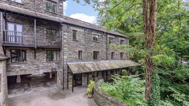 A stone building with multiple windows and balconies, surrounded by lush greenery. - 4 Bed in Ambleside (oc-lr109) (Ambleside)