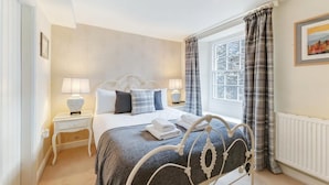 A bedroom with a bed, two bedside tables, a window with curtains, and a radiator. - 3 Bed in Ambleside (oc-lr121) (Ambleside)