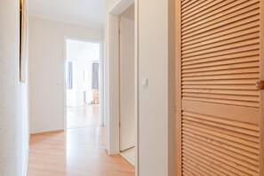 Ein Korridor mit einer Holztür, einer weißen Wand und einem Holzboden.
