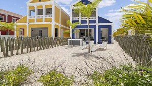 Un hotel de dos pisos, con un área de estar al aire libre techada y un jardín de cactus.