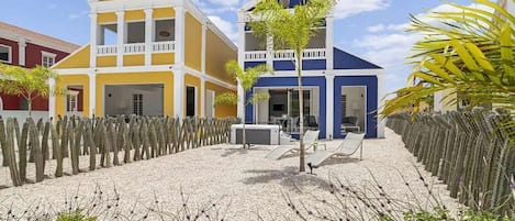 A hotel with a two-story structure, a covered outdoor seating area, and a cactus garden.