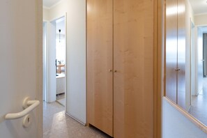 A hallway with a wooden wardrobe, a white door with a handle, and a mirror reflecting part of the room. - Willkommen in Einer Modernen Ferienwohnung (Sellin)