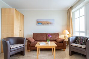 A living room with a brown sofa, two armchairs, a wooden coffee table, and a painting on the wall. - Willkommen in Einer Modernen Ferienwohnung (Sellin)