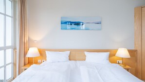 Een hotelkamer met een bed, twee bedlampen, een raam met gordijnen en een schilderij aan de muur.