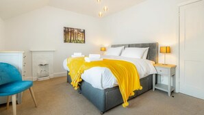 A bedroom with a bed, bedside tables, a chair, a fireplace, and a painting on the wall. - 3 Bed in Ambleside (oc-lr102) (Ambleside)