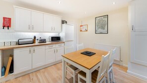 A kitchen with white cabinets, a microwave, a toaster, and a wooden table with chairs. - 2 Bed in Keswick (oc-lr147) (Keswick)
