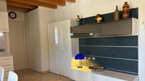 A modern kitchen with white cabinets, a blue pendant light, and decorative items on the shelves. - Spacious, fully furnished two-room apartment with a terrace and a garage, 20 minutes from Orio Airport (Villongo)