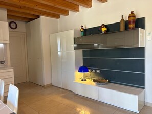 A modern kitchen with white cabinets, a blue pendant light, and decorative items on the shelves. - Spacious, fully furnished two-room apartment with a terrace and a garage, 20 minutes from Orio Airport (Villongo)