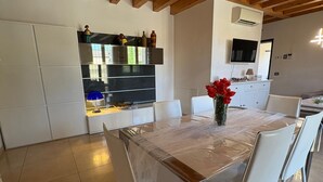 A modern kitchen with white cabinets, a built-in oven, and a dining area with a covered table and chairs. - Spacious, fully furnished two-room apartment with a terrace and a garage, 20 minutes from Orio Airport (Villongo)