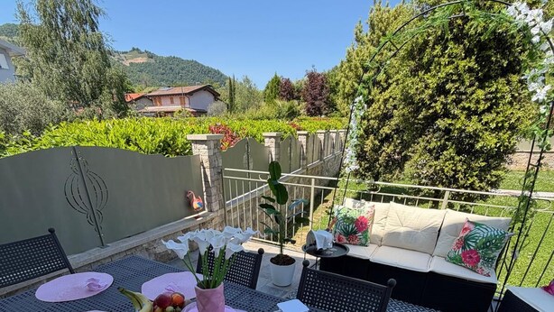 An outdoor patio with a table set for six, surrounded by chairs, a white lantern, and a potted plant. - Spacious, fully furnished two-room apartment with a terrace and a garage, 20 minutes from Orio Airport (Villongo)