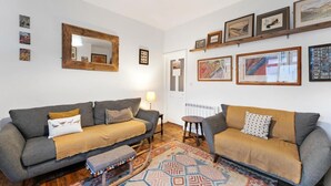 Ein Wohnzimmer mit zwei Sofas, einem Spiegel, gerahmten Bildern und einem gemusterten Teppich.