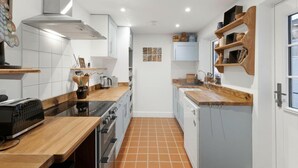Eine moderne Küche mit weißen Schränken, einer Holz Arbeitsplatte, einem Herd und einem Spülbecken.