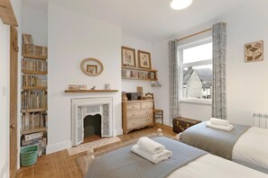 A bedroom with two beds, a fireplace, a dresser, and a bookshelf. - 3 Bed in Coniston (oc-lr198) (Coniston)