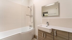 Ein modernes Badezimmer mit einer freistehenden Badewanne, einem wandmontierten Waschbecken und einem großen Spiegel.