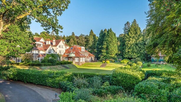 A large estate with multiple buildings, a well-maintained lawn, and dense trees.
