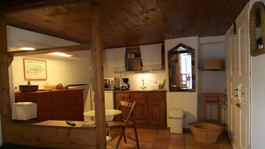 Una cocina acogedora con armarios de madera, una zona de comedor con una silla y un ventanal.