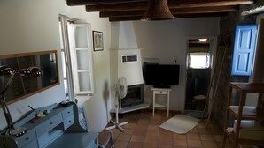 Una habitación con televisión, chimenea, escritorio y silla, y una ventana.