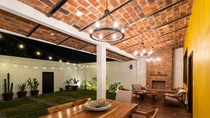 A spacious patio with a wooden table and chairs, surrounded by potted plants and a brick ceiling. - Charming Villa Terrace Outdoor Fireplace (Jiquilpan de Juárez)