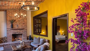 A cozy living room with a brick fireplace, a sofa, a coffee table, and a large mirror. - Charming Villa Terrace Outdoor Fireplace (Jiquilpan de Juárez)