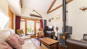 A cozy living room with a sofa, a wooden coffee table, a television, and a fireplace. - 4 Bed in Hawkshead (oc-lr116) (Hawkshead)