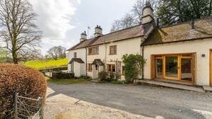 A two-story house with a gravel driveway, wooden doors, and a visible chimney. - 4 Bed in Hawkshead (oc-lr116) (Hawkshead)