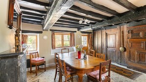 A traditional dining room with a wooden table and chairs, a fireplace, and a large wooden door. - 4 Bed in Hawkshead (oc-lr116) (Hawkshead)