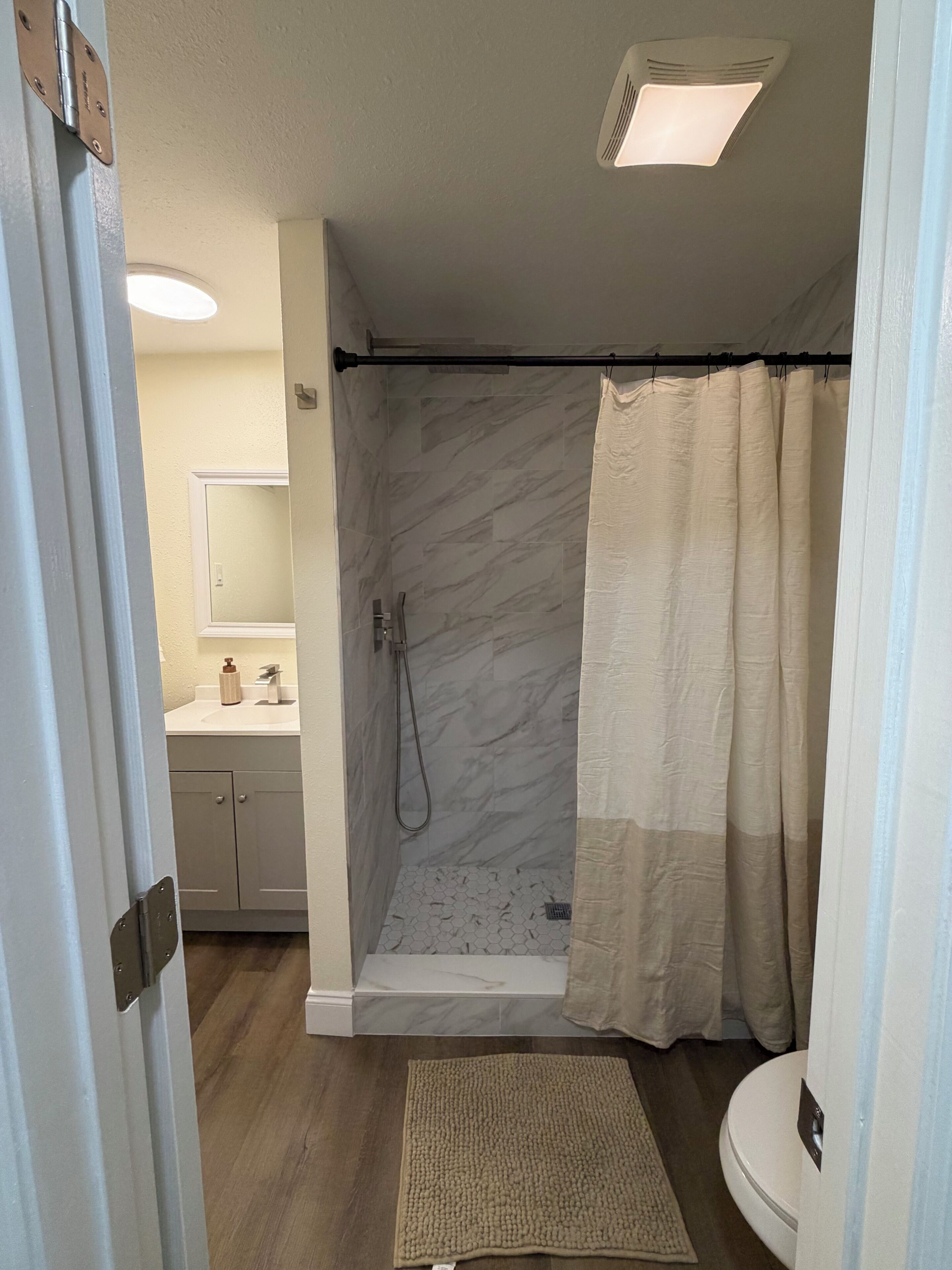 A bathroom with a shower, toilet, and sink.
