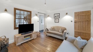 Olohuoneessa on litteänäyttöinen televisio, joka on sijoitettu puiseen kaappiin. Huoneessa on myös beigenvärinen sohva, valkoinen lepotuoli ja puinen ovi.