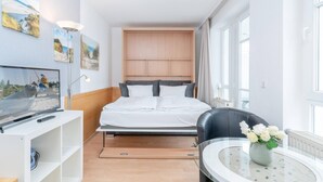 A modern hotel room with a bed, a TV, a desk, and a chair. - Moderne Strandnahe Ferienwohnung in Sellin mit Balkon (Sellin)