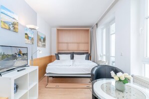 A modern hotel room with a bed, a TV, a desk, and a chair. - Moderne Strandnahe Ferienwohnung in Sellin mit Balkon (Sellin)