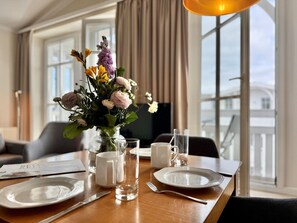 A hotel dining table set with plates, cutlery, a vase of flowers, and a glass of water. - Stylische Ferienwohnung mit Balkon und Wlan im Seepark Sellin (Sellin)