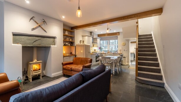 A modern living room with a fireplace, a sofa, a dining area, and a staircase. - 3 Bed in Ambleside (oc-lr052) (Ambleside)