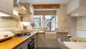 A compact kitchen with a stove, sink, and window overlooking a street. - 3 Bed in Ambleside (oc-lr052) (Ambleside)