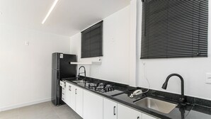 Eine moderne Küche mit schwarzem Arbeitsplatten, weißen Schränken, einem eingebauten Herd und einem schwarzen Kühlschrank.