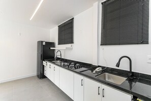 Eine moderne Küche mit schwarzem Arbeitsplatten, weißen Schränken, einem eingebauten Herd und einem schwarzen Kühlschrank.