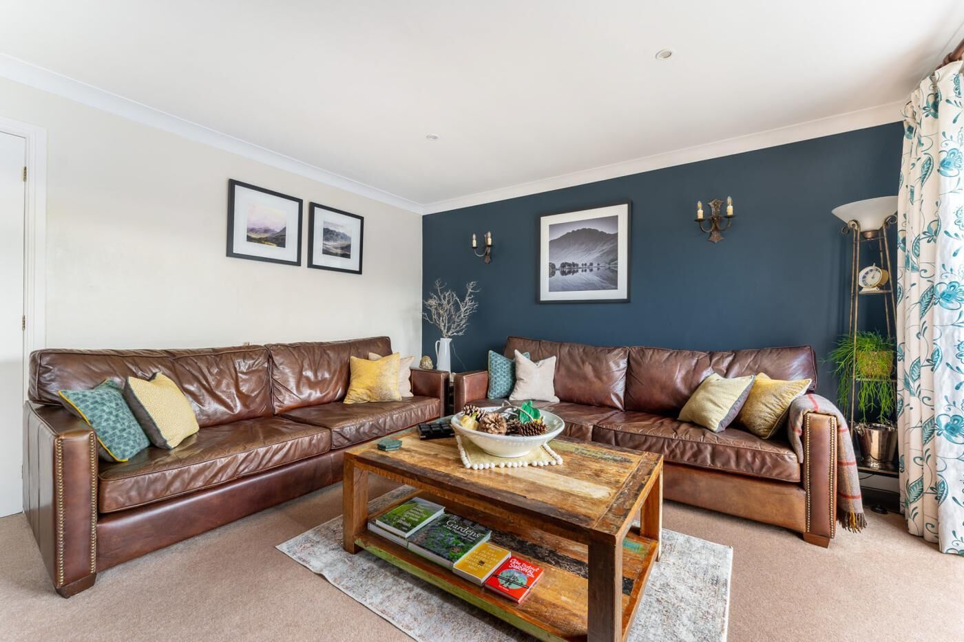 A living room with two brown leather sofas, a wooden coffee table, and a bookshelf.