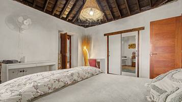 A bedroom with a bed, a desk, a wardrobe, and a ceiling fan.