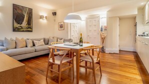 Uma sala de estar moderna com uma mesa de jantar de madeira, um sofá e um quadro na parede.