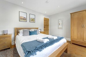 Quarto com cama de madeira, mesas de cabeceira, guarda-roupa e duas imagens emolduradas na parede.