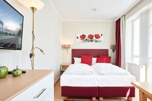 Ein Hotelzimmer mit Bett, Nachttischen, einem Fernseher und einem Bild an der Wand.