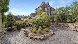 A stone building with a garden and a bench. - 4 Bed in Windermere (oc-lr186) (Windermere)