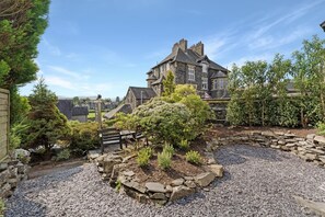 Ein Steinhäuschen mit Garten und Bank.