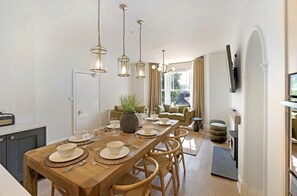 A dining area with a wooden table set for four, surrounded by wicker chairs, under pendant lighting. - 4 Bed in Windermere (oc-lr186) (Windermere)