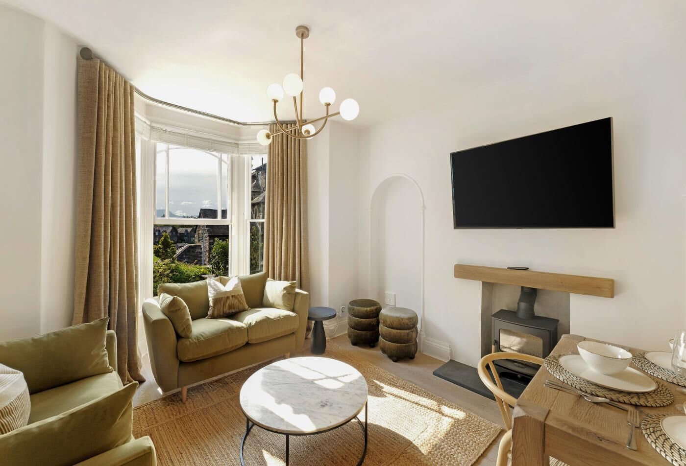 Ein modernes Wohnzimmer mit einer Couch, einem Couchtisch und einem an der Wand befestigten Flachbildfernseher.
