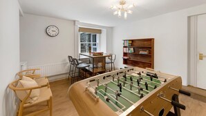 A room with a foosball table, a bookshelf, a clock, and a window with a view. - 4 Bed in Windermere (oc-lr186) (Windermere)